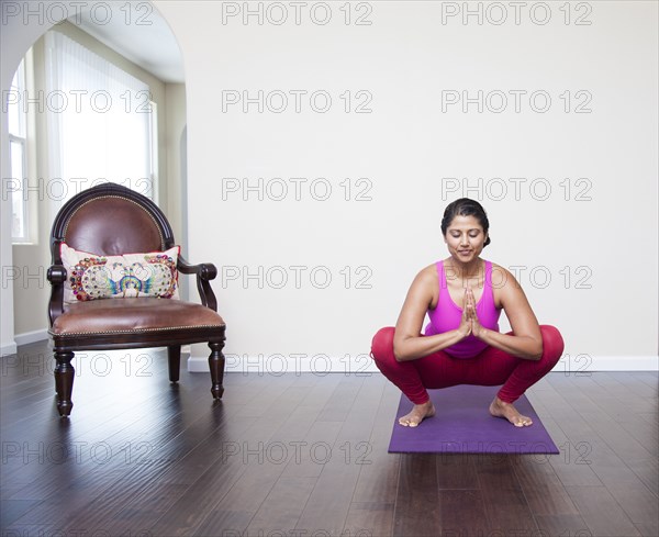 Asian woman practicing yoga in living room