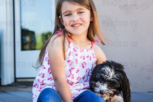 Caucasian girl hugging puppy on patio