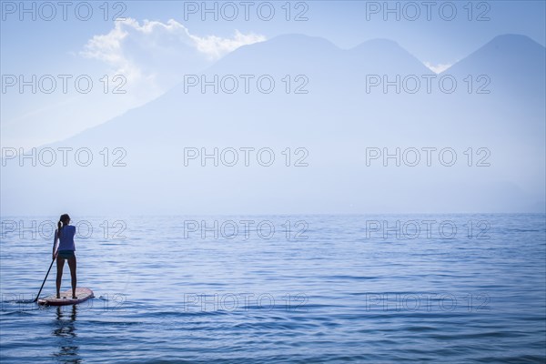 Girl standing on paddleboard in remote lake