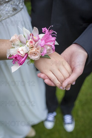 Close up of teenage couple holding hands in prom attire