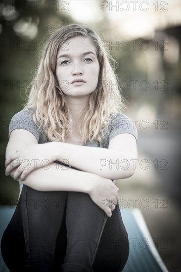 Serious woman hugging her knees