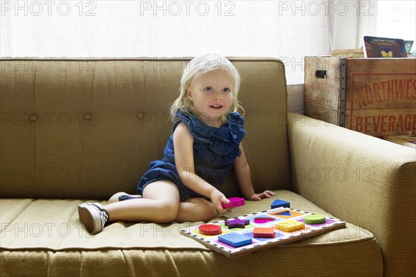 Girl playing with wooden blocks on sofa