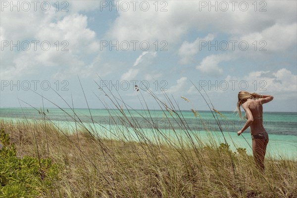 Woman in bikini standing in beach grass
