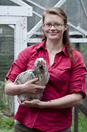 Farmer holding chicken in yard