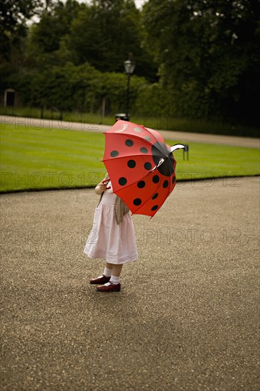 Girl standing under umbrella in park