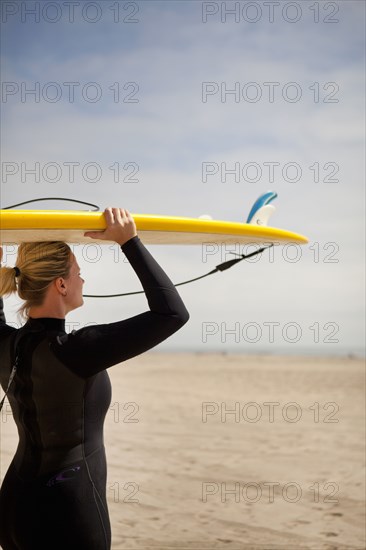 Surfer carrying surfboard on beach