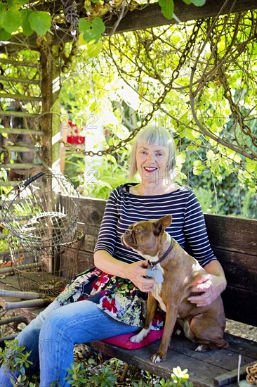 Older Caucasian woman petting dog in garden