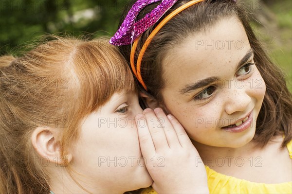Close up of girls whispering outdoors