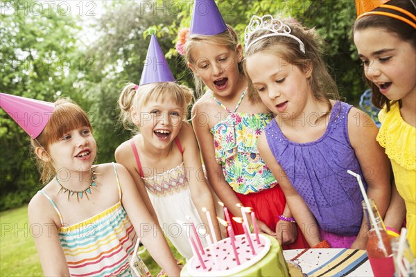 Girls admiring cake at birthday party outdoors