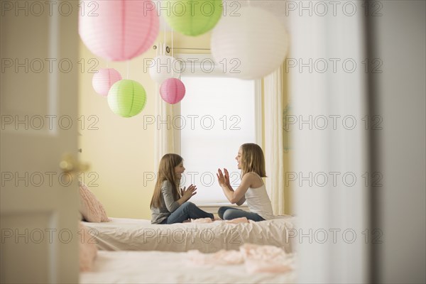 Caucasian girls playing clapping game in bedroom
