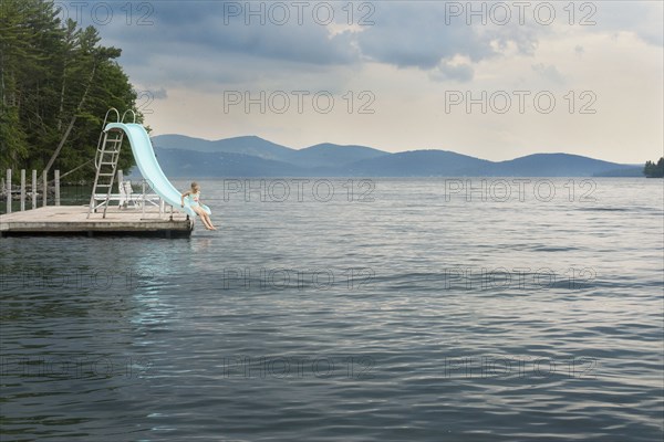 Caucasian girl playing on slide over remote lake