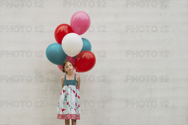 Caucasian girl holding bunch of balloons