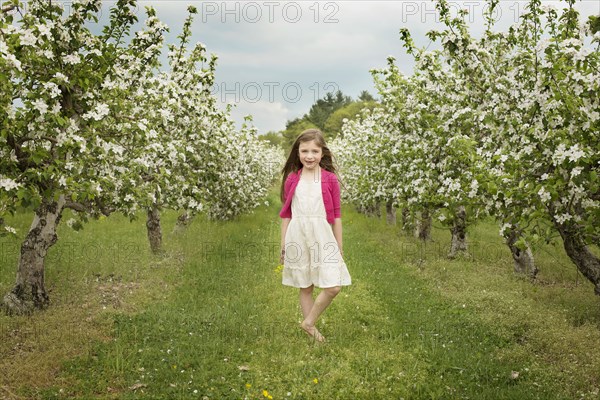 Caucasian girl walking in blooming orchard