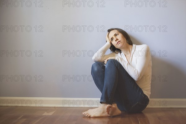 Sad Caucasian woman sitting on floor