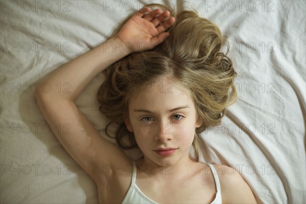 Serious Caucasian girl laying on bed