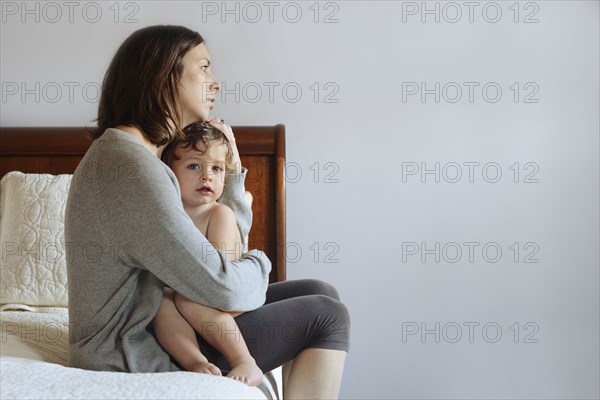 Caucasian mother hugging son on bed