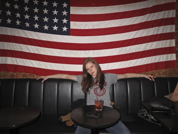 Caucasian woman sitting under American flag in restaurant