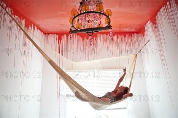 Caucasian woman laying in hammock under dripping ceiling