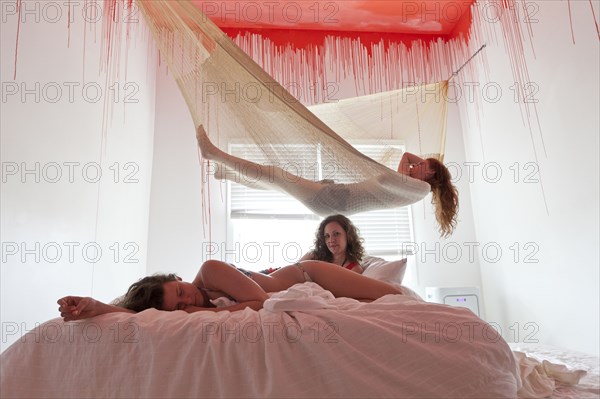 Women laying on bed and hammock under dripping ceiling