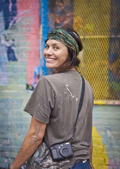 Caucasian woman with paint-splattered shirt smiling