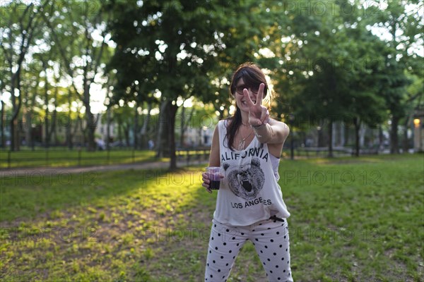 Caucasian woman gesturing peace sign in park