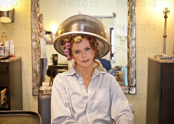 Woman sitting under hair dryer in salon