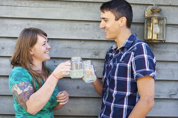 Couple toasting with drinks near wall