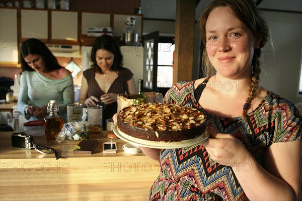 Smiling woman holding cake in kitchen