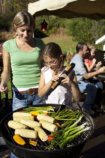 Mother and daughter grilling vegetables on patio