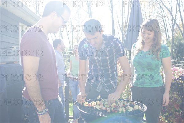 Friends grilling vegetables in backyard