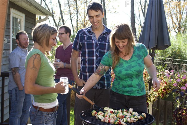 Friends grilling vegetables in backyard