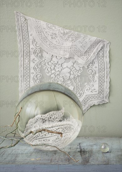 Lace hanging over crystal balls and branches on table