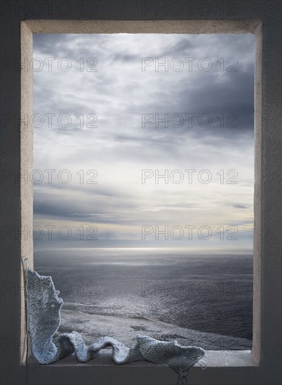 Knitted scarf in window over seascape