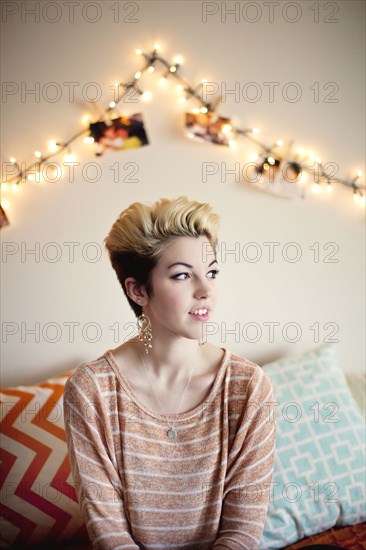 Woman sitting under string lights in bedroom