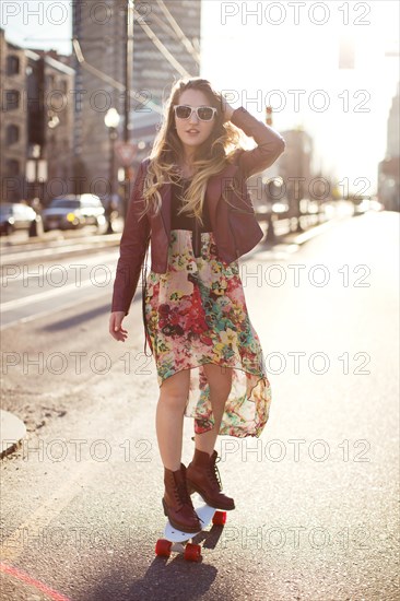 Woman riding skateboard on city sidewalk