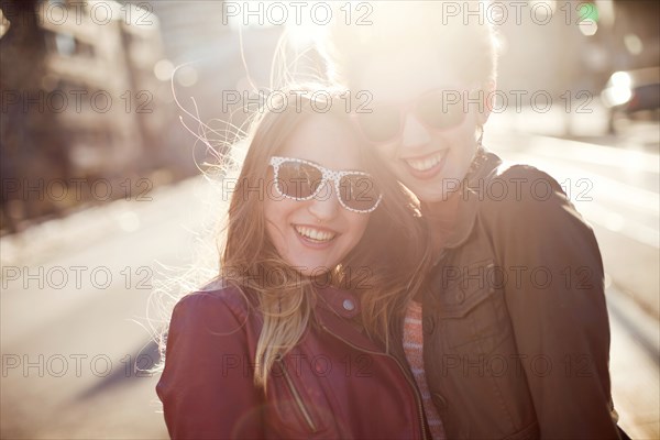 Women hugging on sunny city sidewalk