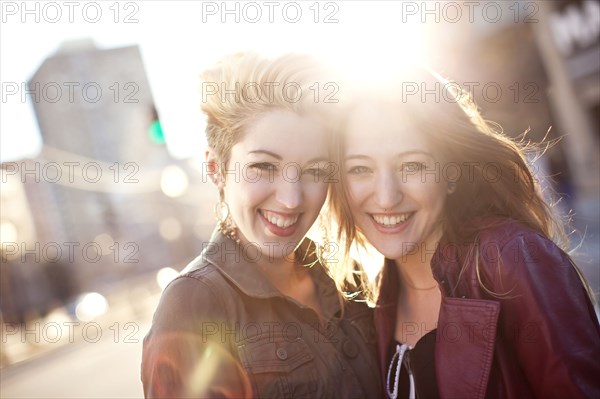 Women hugging on sunny city sidewalk