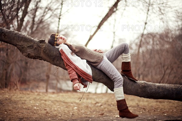 Caucasian woman laying in tree in rural field