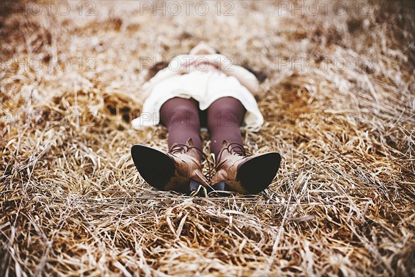 Caucasian teenage girl laying in tall grass