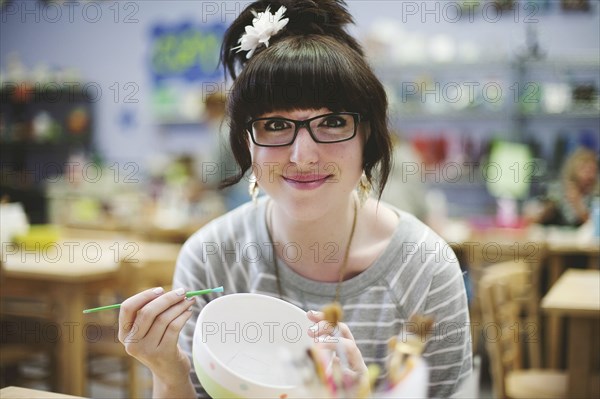 Caucasian teenage girl painting pottery in class