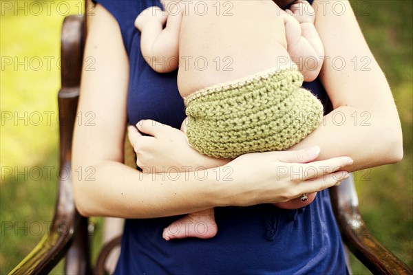 Close up of girl holding baby in armchair