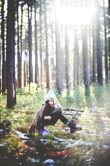 Woman sitting on log in forest