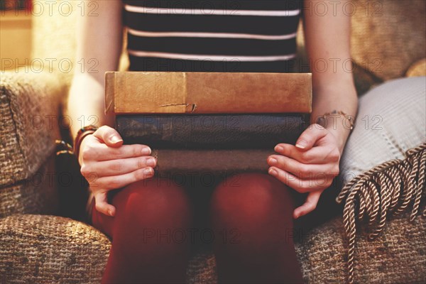 Close up of woman sitting on armchair holding books
