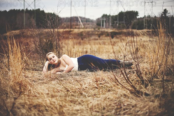 Teenage girl laying in tall grass in park