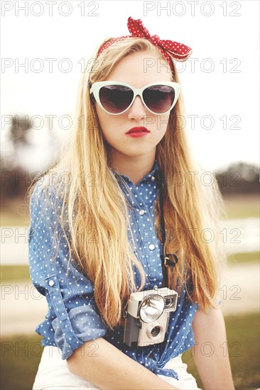 Caucasian woman wearing sunglasses and instant camera