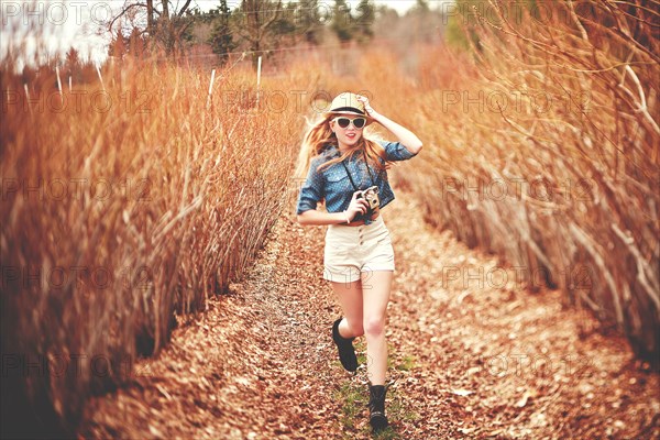 Caucasian woman carrying instant camera on dirt path