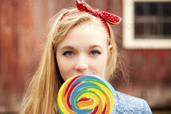 Caucasian teenage girl licking lollipop