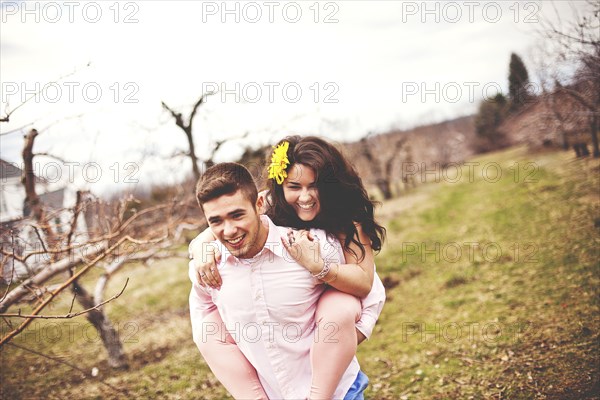 Man carrying girlfriend piggyback in vineyard