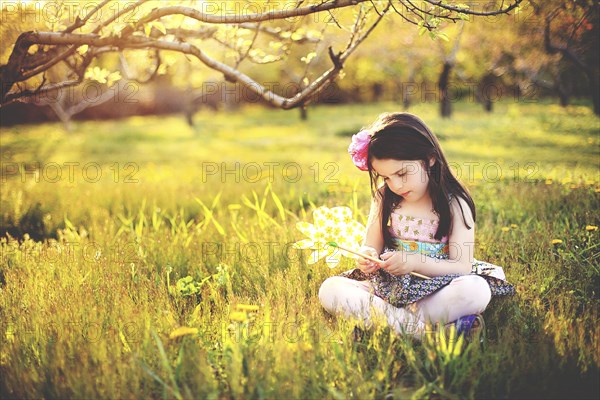 Girl playing with pinwheel in rural field