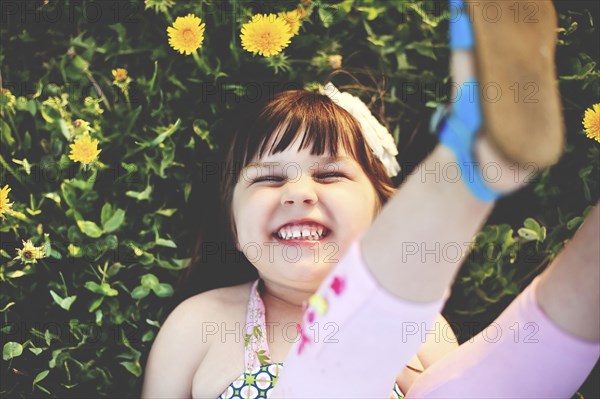 Smiling girl playing in grass with flowers